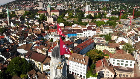 Hermosa-E-Interesante-Toma-Giratoria-De-Drones-Que-Muestra-La-Iglesia-De-Grossmunster-En-Zúrich,-Suiza-Y-Sus-Alrededores-En-El-Fondo