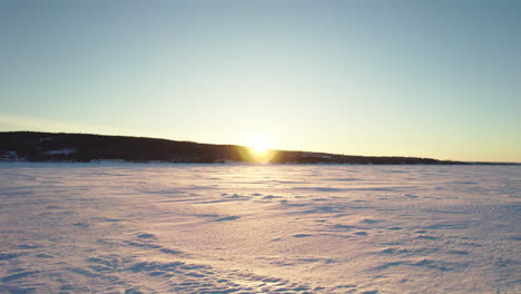 Flying-drone-above-a-frozen-lake-in-canada-at-golden-hour