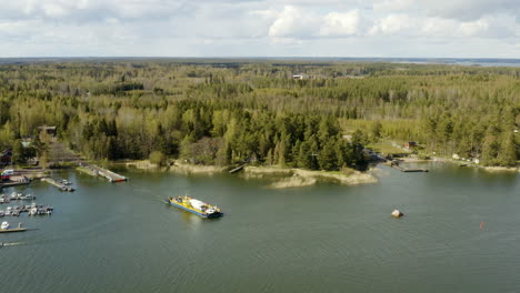 Aerial-view-panning-away-from-a-cable-ferry-in-the-archipelago-of-Porvoo,-sunny,-spring-day,-in-Uusimaa,-Finland---pull-back,-drone-shot