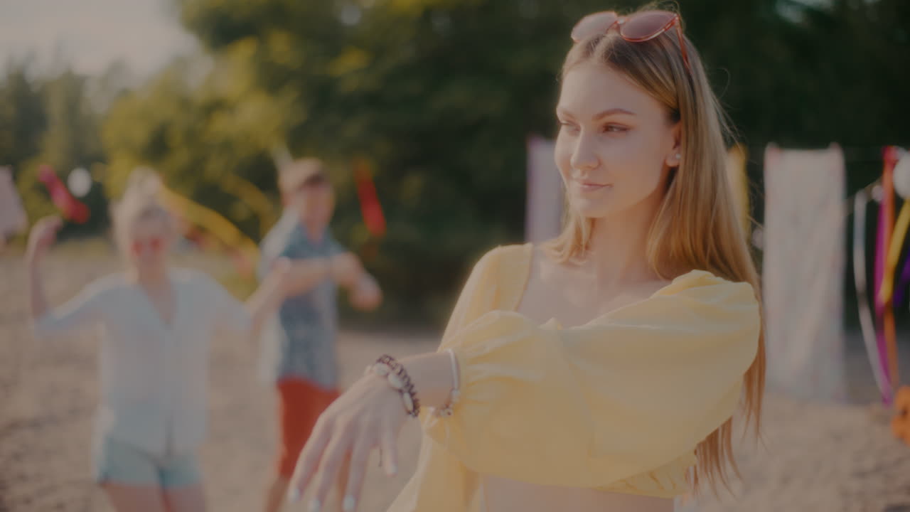 красивая блондинка танцует на пляже против друзей.