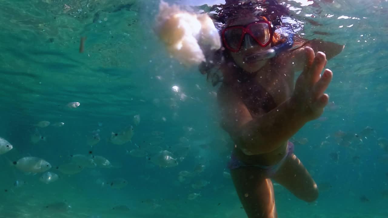 빵을 먹이는 물고기 떼에 둘러싸인 빨간 머리 소녀의 수중 장면