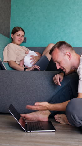 parents of a newborn child working remote at home. caucasian couple discussing something on laptop. vertical video
