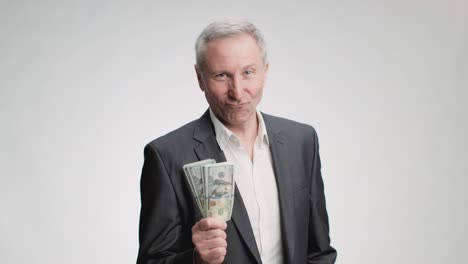 jubilación exitosa y riqueza. rico hombre de edad avanzada confiado con traje mostrando pila de dinero a la cámara y sonriendo