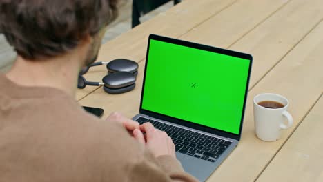 hombre trabajando en una computadora portátil con pantalla verde