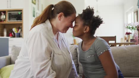 Happy-caucasian-woman-and-her-african-american-daughter-smiling-in-living-room