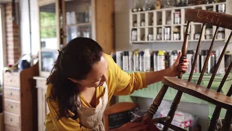 mature asian woman restoring furniture in workshop at home - shot in slow motion