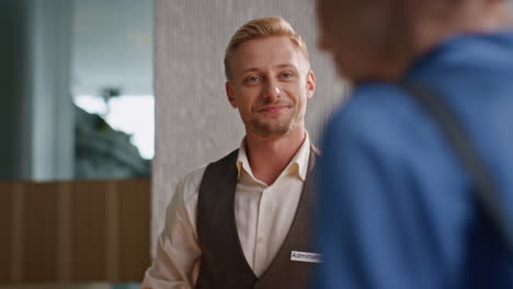 friendly concierge talking guests at reception closeup. smiling man in uniform