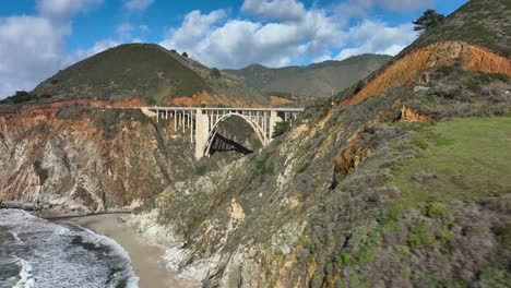 aerial shot sweeping over green pasture to reveal the bixby bridge, highway 1, california