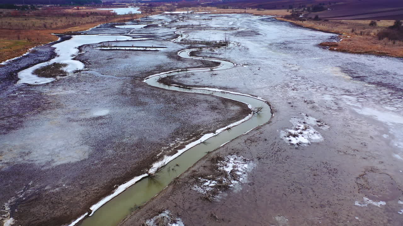Narrow dirty river. Ecological problems with water. Dried place with a stream with muddy water floating in the countryside. Aerial view.