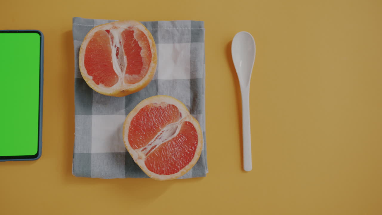Grapefruit slices and mobile phone on a yellow surface