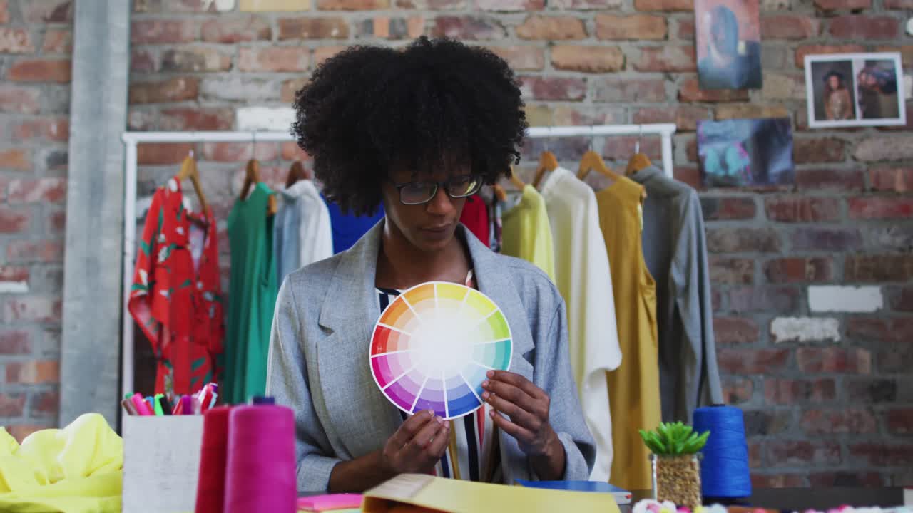 diseñadora de moda afroamericana mostrando la paleta de colores mirando a la cámara y sonriendo