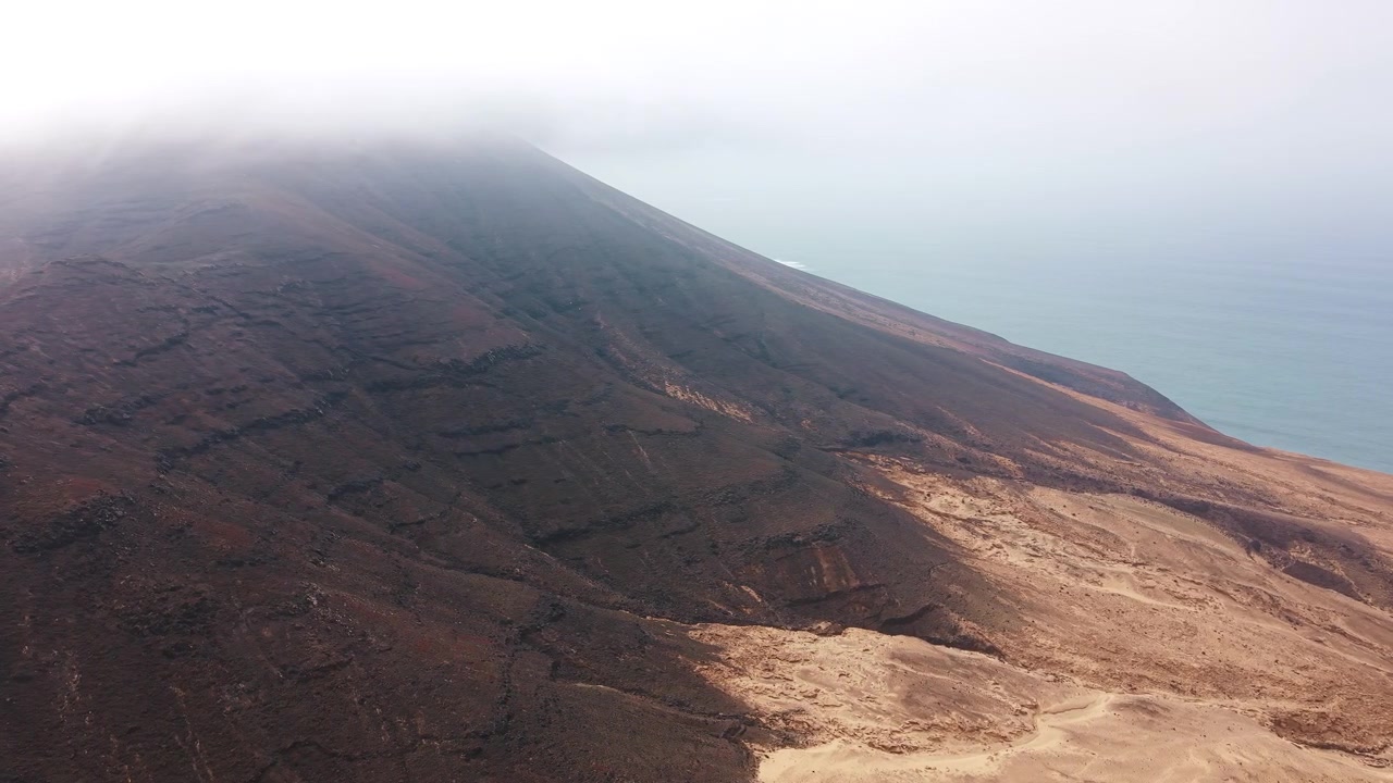 Vista aerea di un pendio montuoso vulcanico che incontra l'oceano