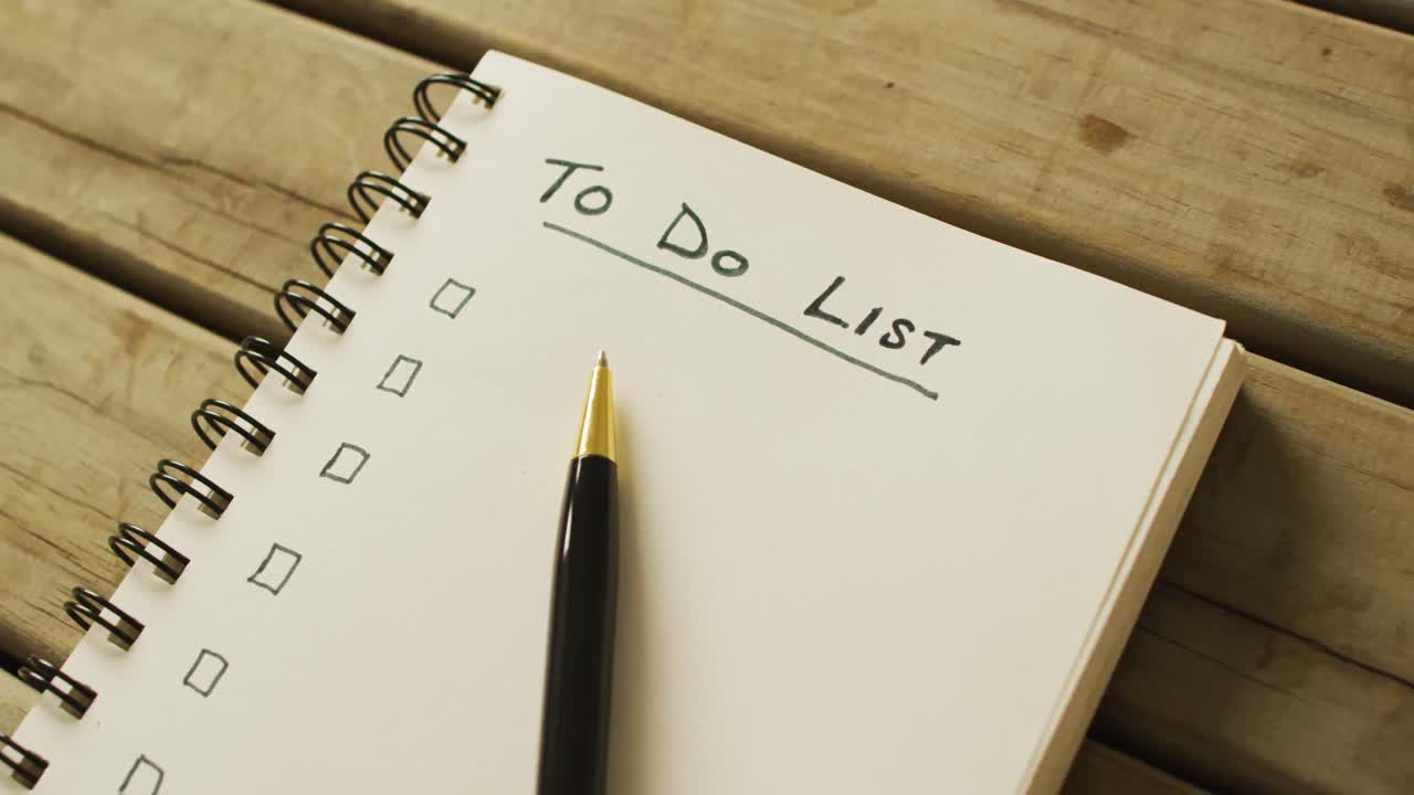 Video of notebook with to do list and copy space and pen on wooden surface