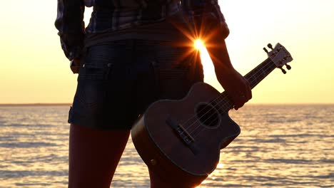 woman at sunset holding a ukulele