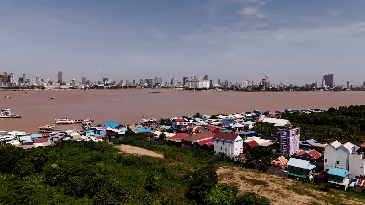 Ripresa laterale con drone sopra un villaggio di fronte alla città di Phnom Penh sulle rive del Mekong. La telecamera si sposta da destra a sinistra