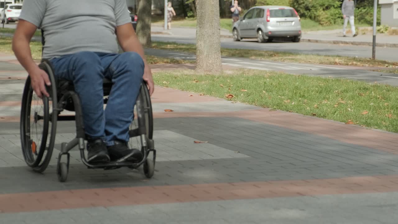 hombre con discapacidad en silla de ruedas camina por el callejón del parque