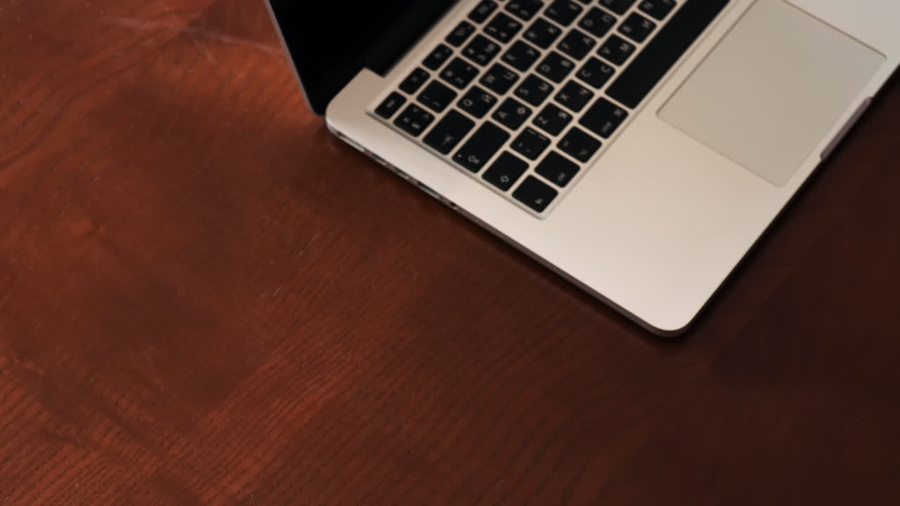 A man puts a cup of coffee, laptop on the wooden table. Top view