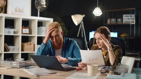 portrait of emotional man and woman finding mistake in business project indoors.