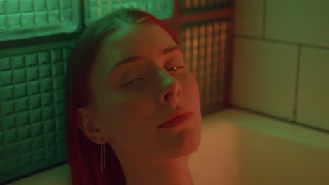 portrait of attractive girl resting in bathtub under colorful light