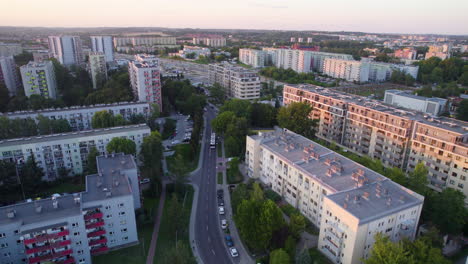 Toma-Aérea-Hacia-Atrás-De-La-Carretera-Entre-Un-Gran-Distrito-Residencial-Con-Bloques-De-Apartamentos-De-Gran-Altura-Al-Atardecer---Cracovia,-Polonia