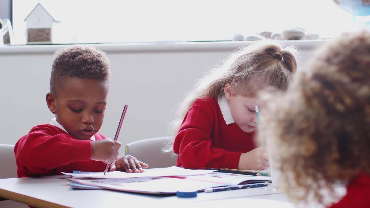 Young black schoolboy and classmates drawing at infant school art class, close up, selective focus