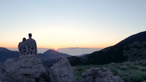 una pareja disfrutando de un amanecer en la cima de una montaña