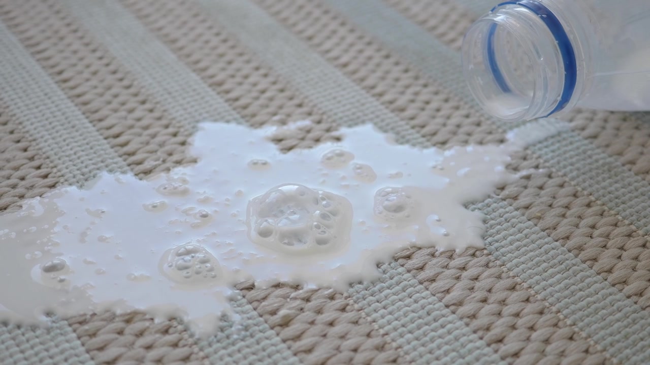 Latte versato da una bottiglia di plastica su un tappeto testurizzato