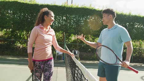 video de una feliz pareja biracial jugando al tenis en la cancha