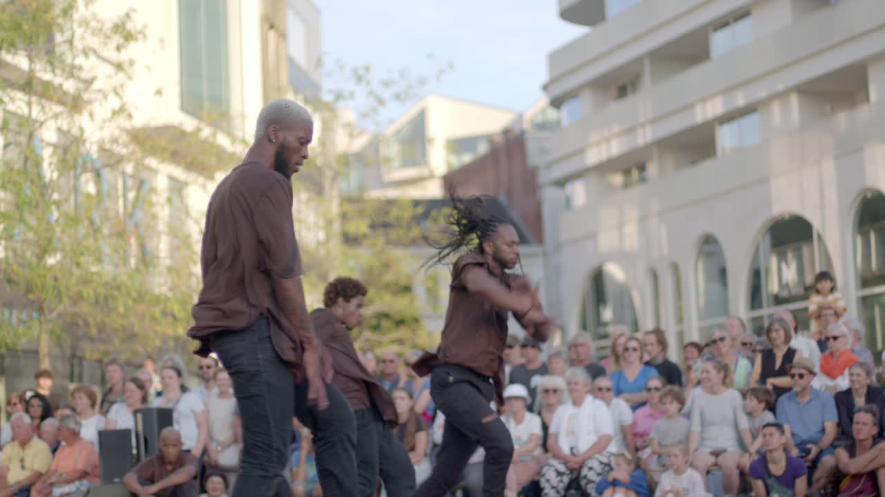 Group of ethnic man performing street dance during theatre festival on the streets, Handheld shot