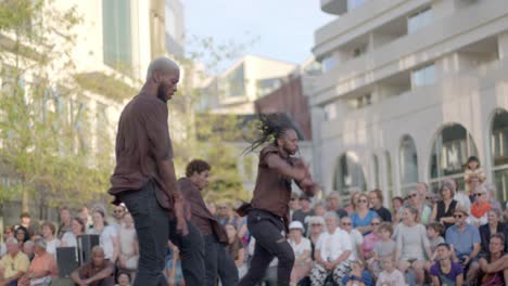 group of ethnic man performing street dance during theatre festival on the streets, handheld shot