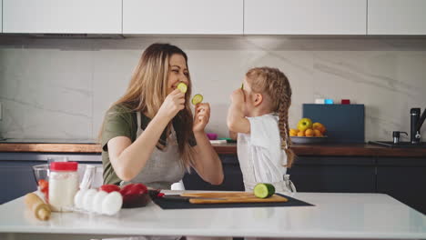 madre en la cocina y pequeña hija vestida con delantales