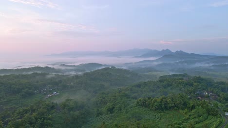 Forest-covered-mountains-on-foggy-morning-in-Indonesia,-aerial-view