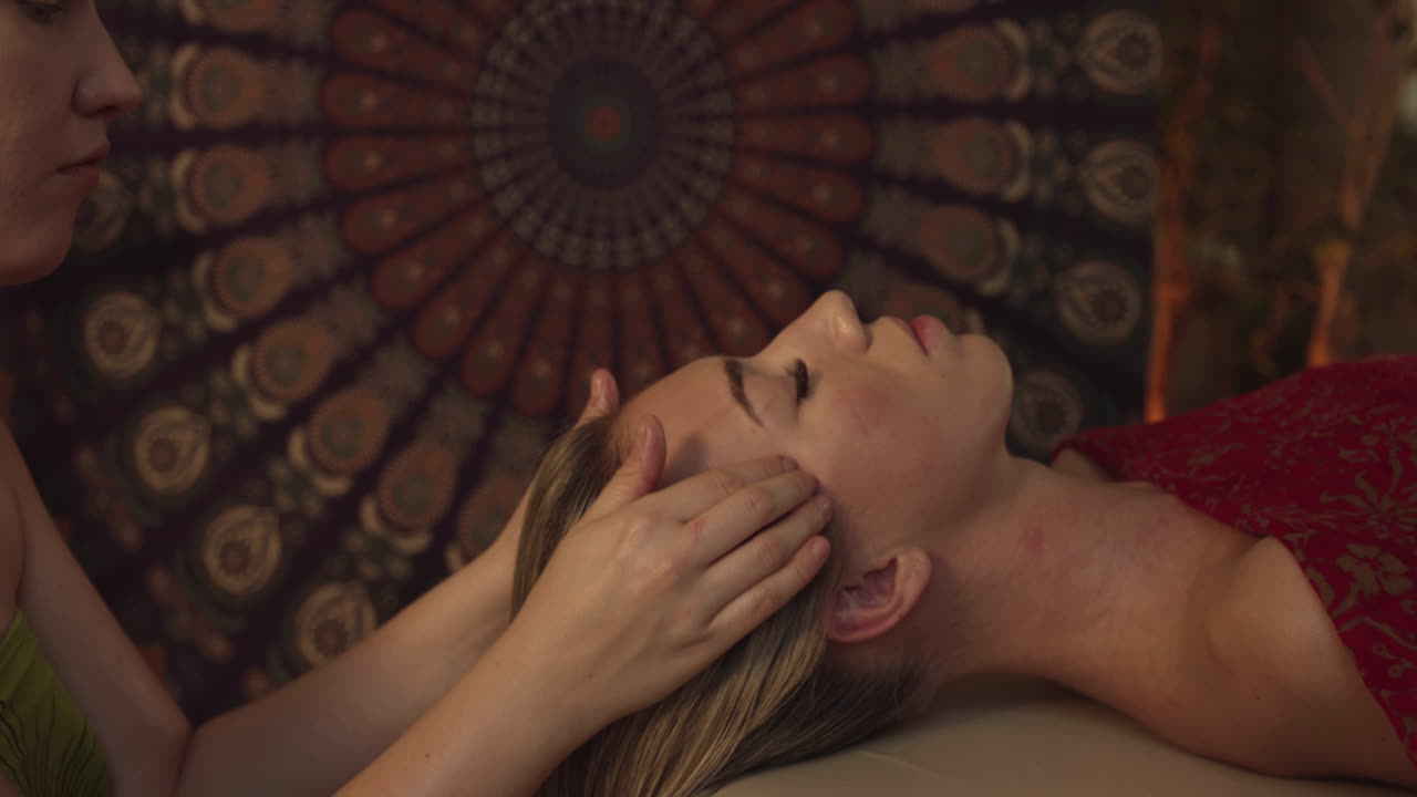 Massaggio viso. Giovane donna che si fa massaggiare il viso in un centro benessere. Trattamento di bellezza per la pelle in una spa. Donna distesa con gli occhi chiusi mentre la massaggiatrice le tocca la pelle del viso