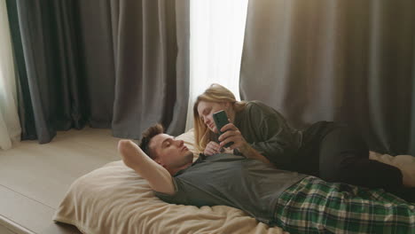 pareja relajándose en la cama con un teléfono inteligente