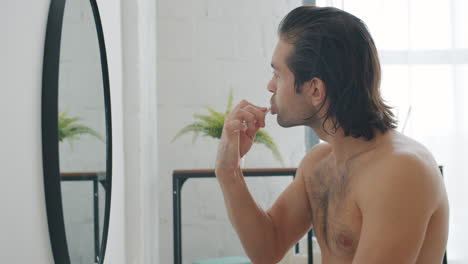 hombre cepillándose los dientes en el baño