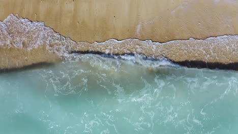 Schöne-Tropische-4K-Strandantenne---Ein-Blick-Aus-Der-Vogelperspektive-Auf-Meereswellen,-Die-Von-Oben-Gegen-Einen-Leeren-Strand-Prallen