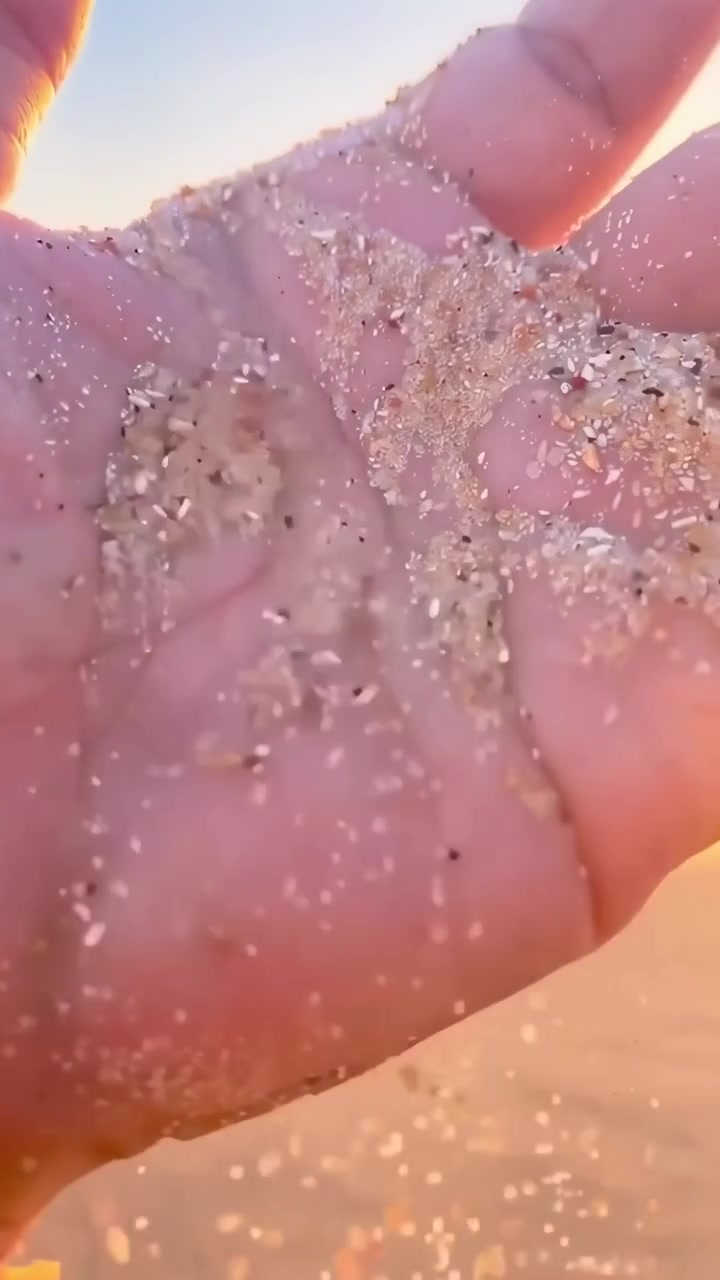 Sabbia che scivola tra le dita al tramonto sulla spiaggia