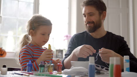 Father-And-Daughter-Making-Halloween-Masks-At-Home-Together