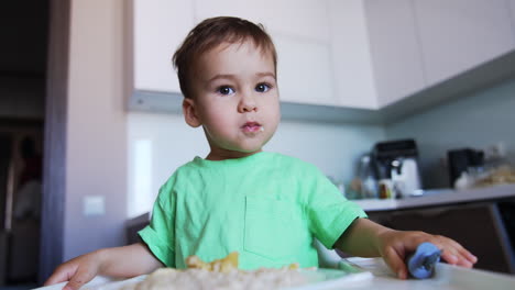 little boy opens his mouth wide to eat food from fork. toddler studying eating himself. low angle view.