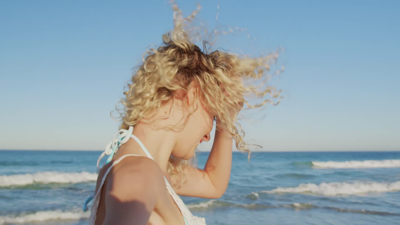해변 4k를  ⁇ 고 있는 미소 짓는 젊은 여성