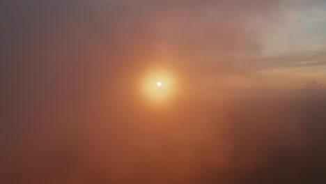 bright dramatic sun reveal at sunset, sunrise, flying through light wispy foggy golden clouds