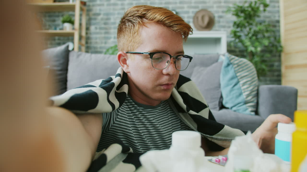 Sick Young Man Taking Medication at Home