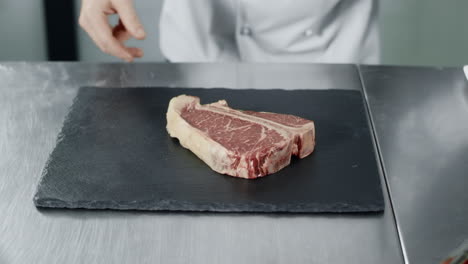 chef preparing to cook at kitchen restaurant. closeup chef hands with raw steak.