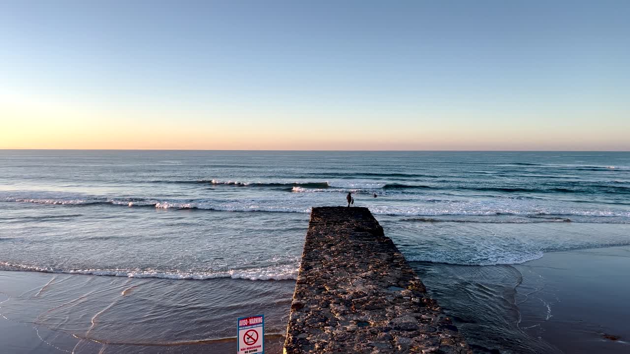 close view of coach training surfers at the tip of the pier in Portugal