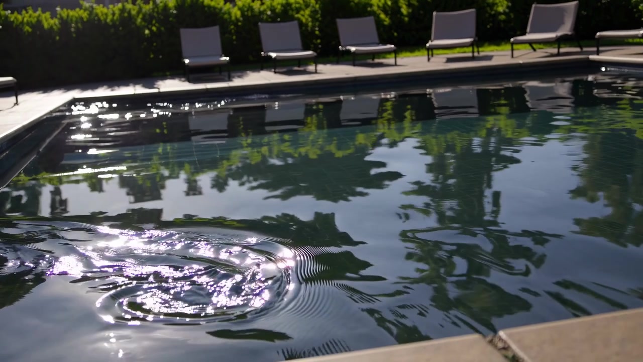Sollys reflekteres på krusende swimmingpoolvand