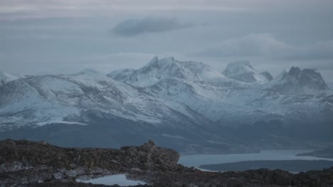 time lapse of norwegian snowy mountains, clouds passing by over a beautiful scenic view as sun slowly sets