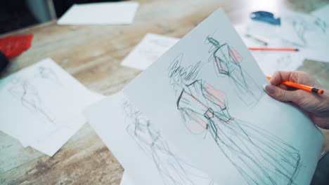 fashion designer is looking at different sketches and throws away unsuitable one. workplace of a dressmaker with many drawings of modern dresses written on papers on the table.