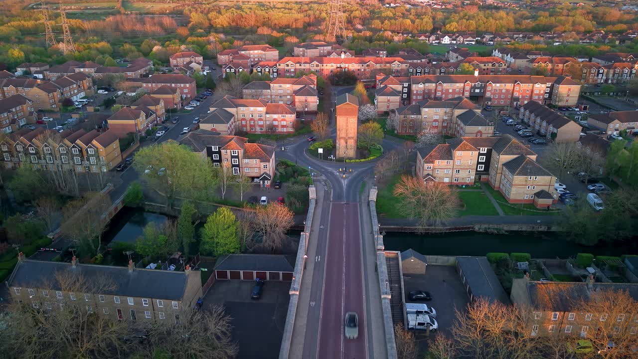 Aerial view towards sunlit water tank tower on Enfield island village roundabout near London city
