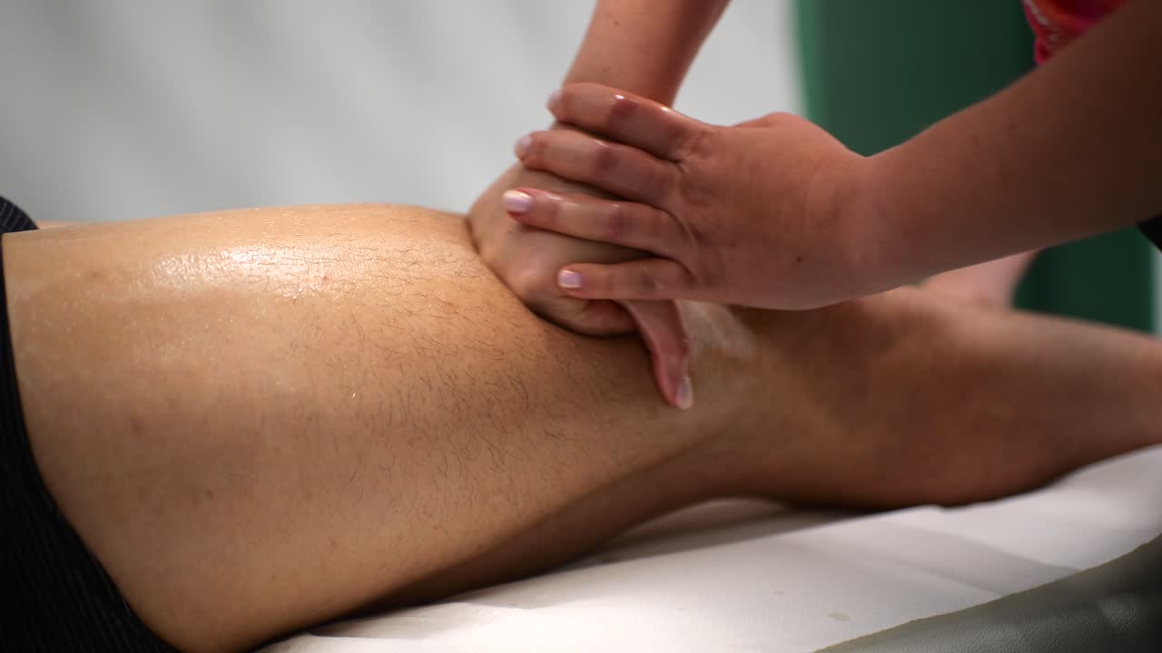 Massaggio sportivo ai quadricipiti usando la tecnica del pugno in un ambiente studio, primo piano