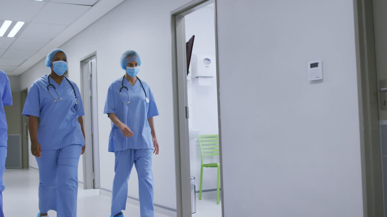 Forskellige kvindelige kirurger iført mundbind, der går på en hospitalsgang